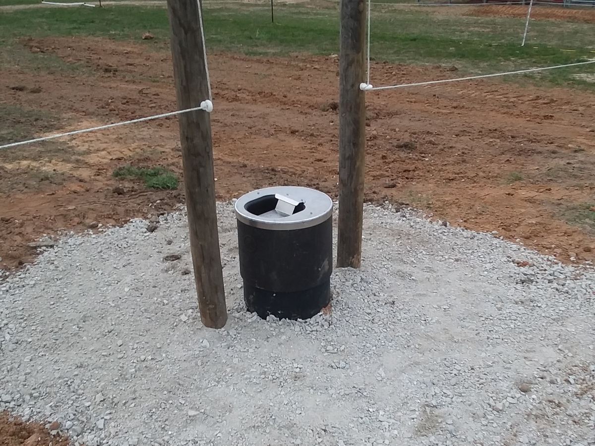 An energy free waterer set level on a gravel pad and plumbed in on the fence line between two paddocks, so a single tank serves livestock on both sides